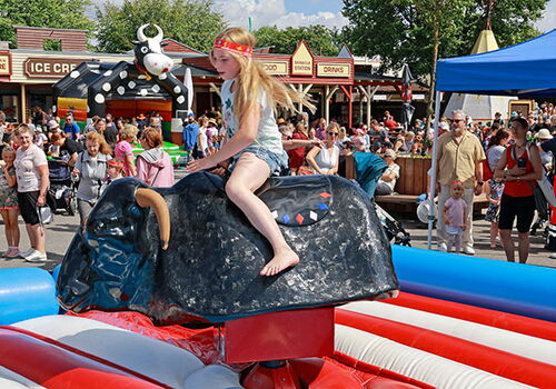 Kind reitet einen mechanischen Bullen auf Jahrmarkt.