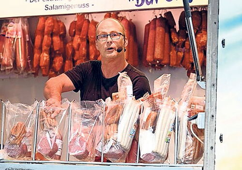 Ein Mann verkauft Salami an einem Marktstand.