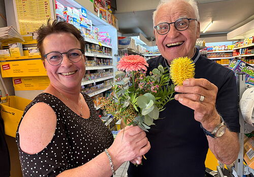 Mann und Frau lächeln mit Blumenstrauß im Laden.