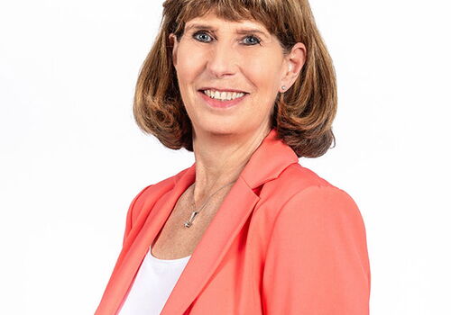 Frau in korallfarbenem Blazer vor weißem Hintergrund
