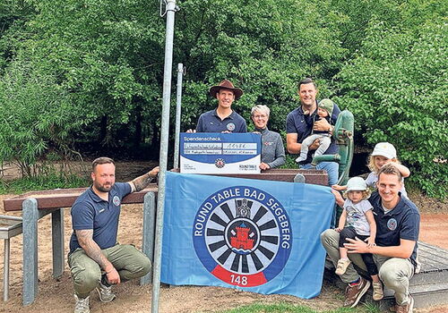 Gruppe mit Scheck und Round Table Banner im Freien