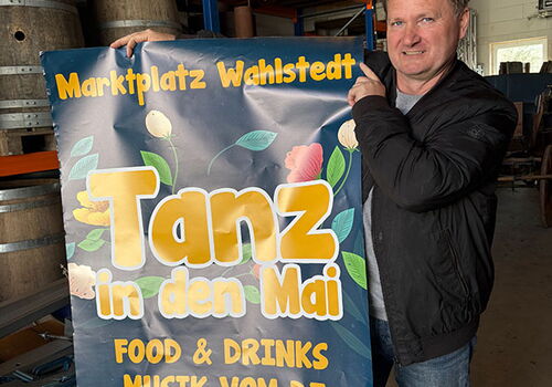 Mann hält Plakat für Tanz in den Mai in Wahlstedt