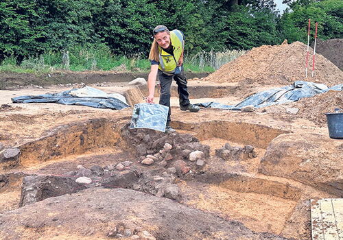 Archäologe zeigt Funde auf archäologischer Ausgrabung.