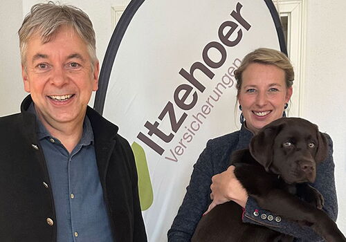 Zwei Personen mit Hund vor Itzehoer Banner.