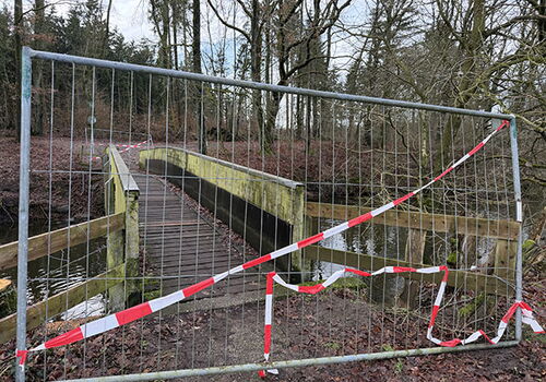Absperrung vor einer gesperrten Brücke im Wald.