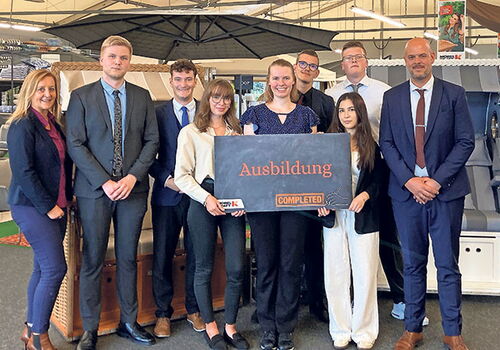 Gruppe von jungen Erwachsenen mit Schild 'Ausbildung completed'.