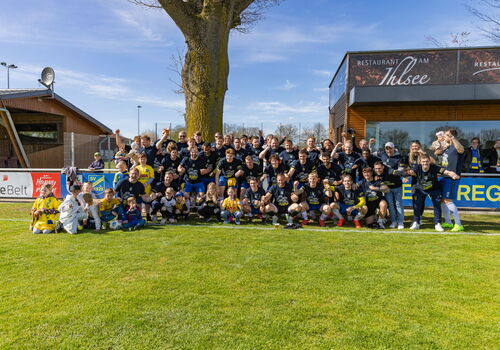 Fußballteam feiert vor einem Restaurant am See.