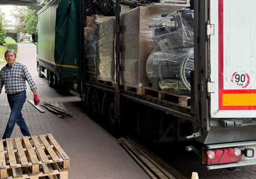 Lkw mit geöffnetem Anhänger und Paletten beladen.