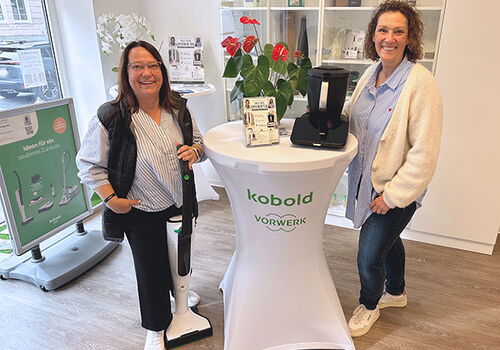 Zwei Frauen im Vorwerk-Geschäft neben einem Tisch mit Geräten.