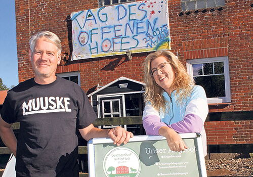 Zwei Personen vor einem Schild am Tag des offenen Hofes.