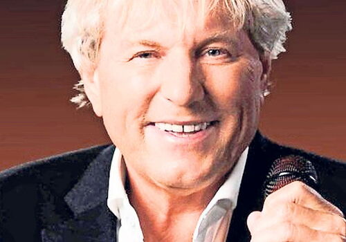 Bernhard Brink lächelt und hält ein Mikrofon