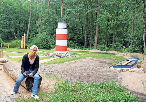 Person sitzt vor einem kleinen Leuchtturm im Wald.