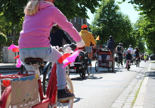 Kinder fahren in einer Gruppe Fahrrad auf einer Straße.