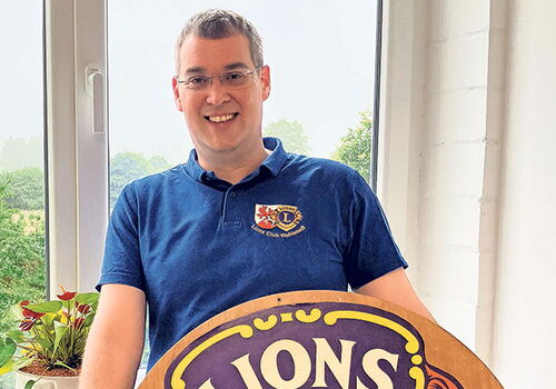 Person mit Lions Club-Schild neben einem Fenster
