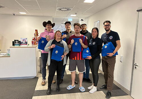 Gruppe von Menschen hält blaue Decken in einem Büro.