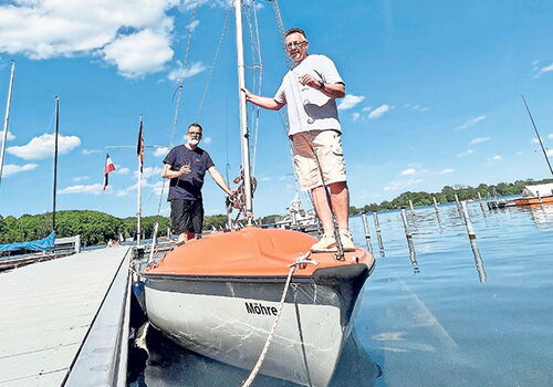 Männer bei Bootstaufe in sonnigem Hafen