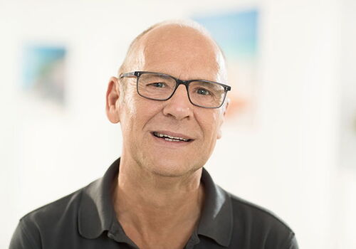 Mann mit Brille lächelt in die Kamera.