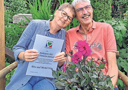 Paar auf Bank mit Blumen und Urkunde im Garten