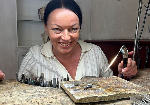 Frau bei der Schmuckherstellung an einem Werktisch.