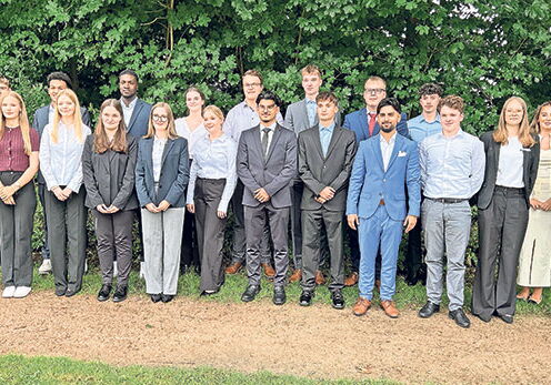 Gruppe von 19 jungen Erwachsenen in formeller Kleidung im Freien.