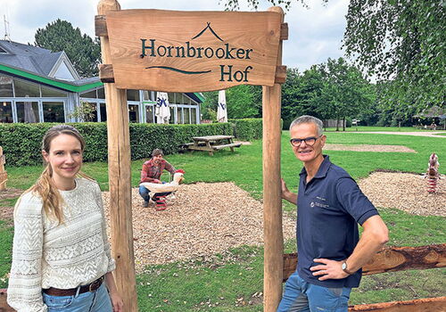 Zwei Personen vor dem Schild 'Hornbrooker Hof'.