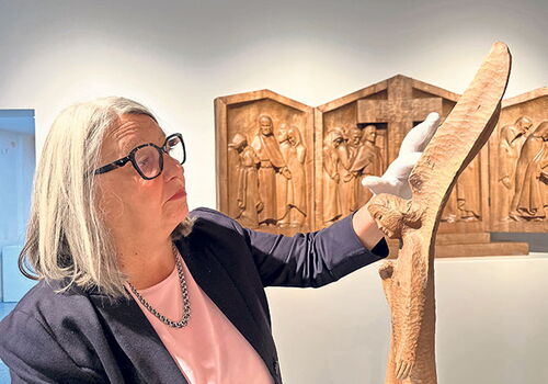 Frau betrachtet Holzskulptur in einer Galerie.