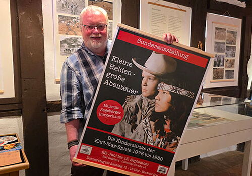 Mann hält ein Plakat zur Karl-May-Ausstellung im Museum.