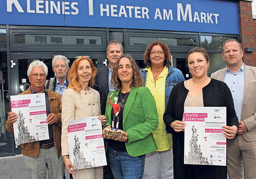 Gruppe vor dem Kleinen Theater am Markt mit Plakaten.
