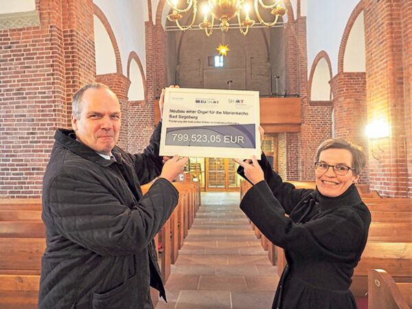 Schleswig-Holsteins Landwirtschaftsminister Werner Schwarz bei der symbolischen Scheckübergabe an Kirsten Geißler, Vorsitzende des Kirchengemeinderats und Mitglied im Vorstand des Fördervereins Marienkirche. Mit dabei auch dessen 1. Vorsitzender, Prof. As