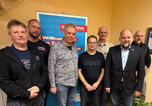 Gruppe von Männern vor einem Banner mit Handwerksschriftzug.