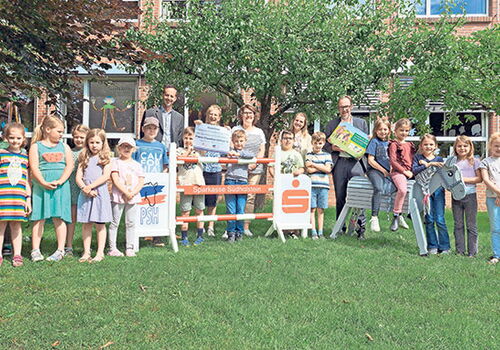 Gruppe von Kindern und Erwachsenen auf einer Wiese.