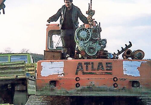 Mann steht auf einem Bagger mit Motor in der Luft.