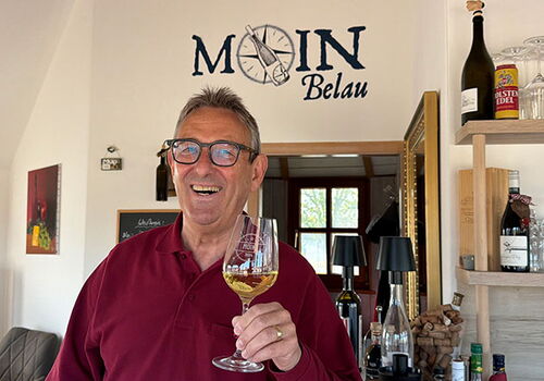 Mann mit Weinglas in einem gemütlichen Raum.