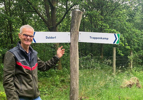 Person neben Wegweiser im Wald zu Daldorf und Trappenkamp.
