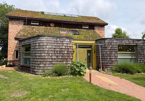 Ökohaus mit begrüntem Dach und Solarmodulen.