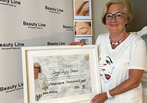 Frau hält Zertifikat vor Beauty Line Banner.