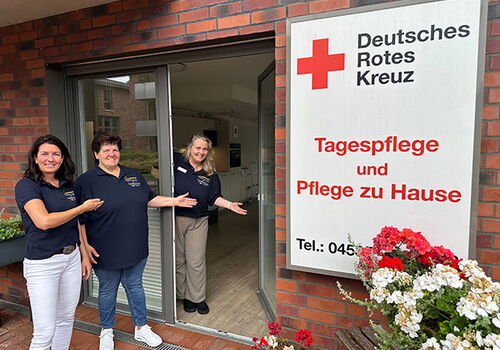 Drei Frauen vor einer Tagespflegeeinrichtung des Deutschen Roten Kreuzes.