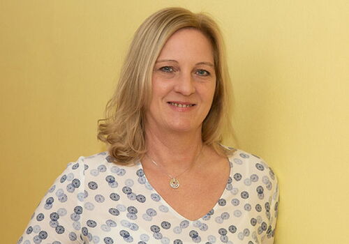 Lächelnde Frau vor gelbem Hintergrund.