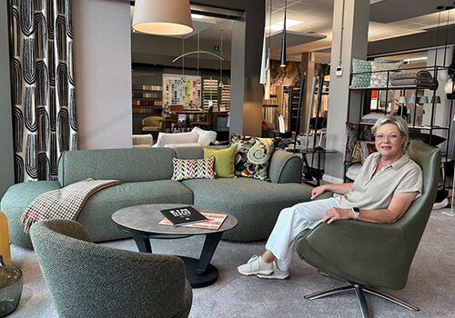 Frau sitzt auf einem grünen Stuhl in einem modernen Wohnzimmer.