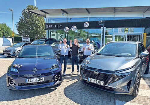 Drei Personen vor Renault-Autos vor einem Autohaus.