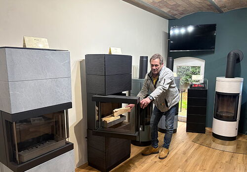 Mann legt Brennholz in modernen Kamin in einem Ausstellungsraum.