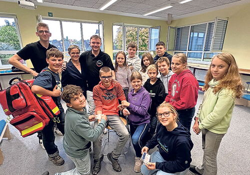 Gruppe von Schülern im Klassenzimmer mit zwei Erwachsenen.