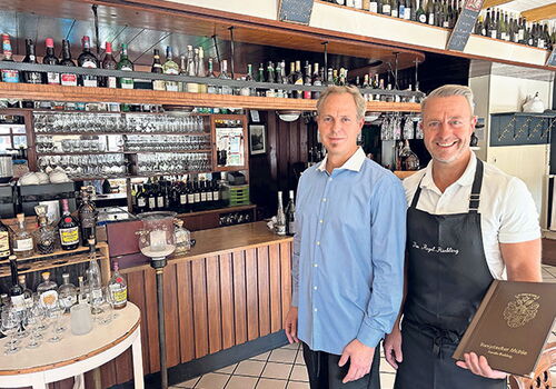 Zwei Männer vor einer Bar mit Getränken.