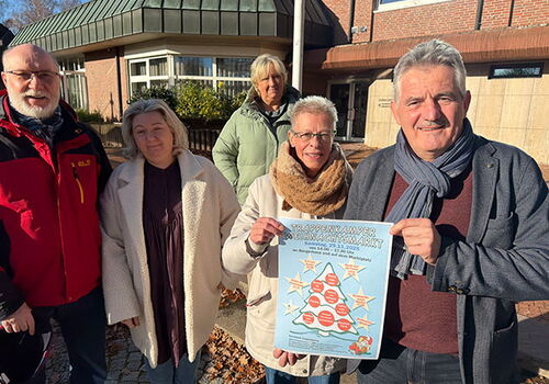 Fünf Personen halten ein Weihnachtsmarkt-Plakat.