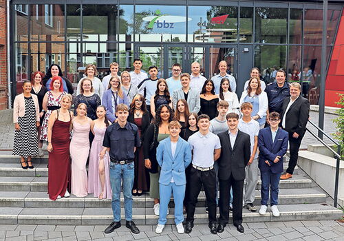 Gruppenfoto von Absolventen auf einer Treppe vor einem Gebäude.