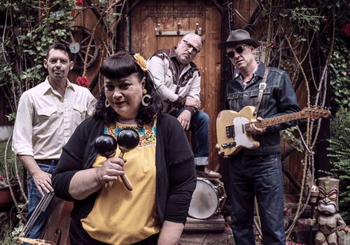 Vier Musiker posieren mit Instrumenten im Freien.