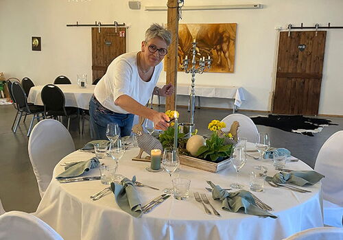 Frau dekoriert Tisch mit Kerzen und Blumen.