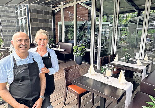 Zwei lächelnde Personen in einem Restaurant.