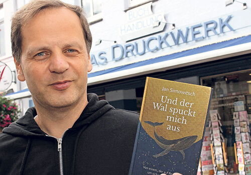 Mann hält Buch vor Buchhandlung 'Das Druckwerk'.