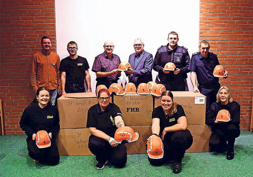 Gruppe von Menschen präsentiert orange Helme.